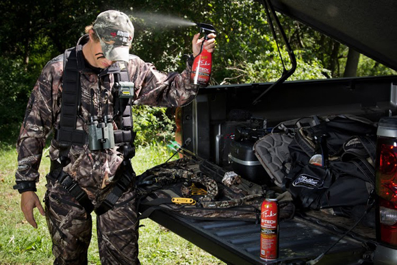 Hunter spraying tinks scent on himself by his truck