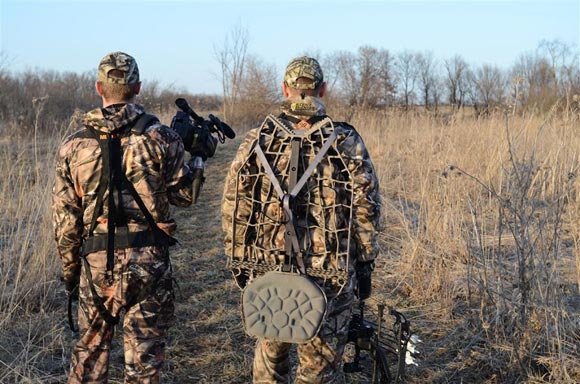 2 Hunters, one holding a camera and the other a bow