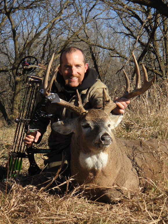 Hunter with his bow behind deer on ground