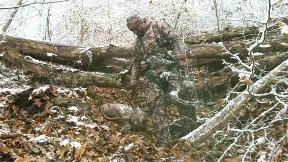 Hunter next to deer on forest floor