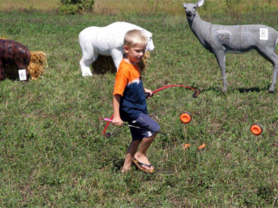 kid holding bow walking by animal targets