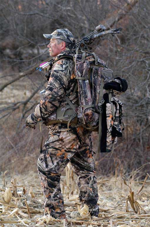Bowhunter in corn field with backpack on.
