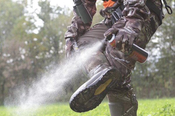 Bowhunting spraying boots with scent eliminating spray