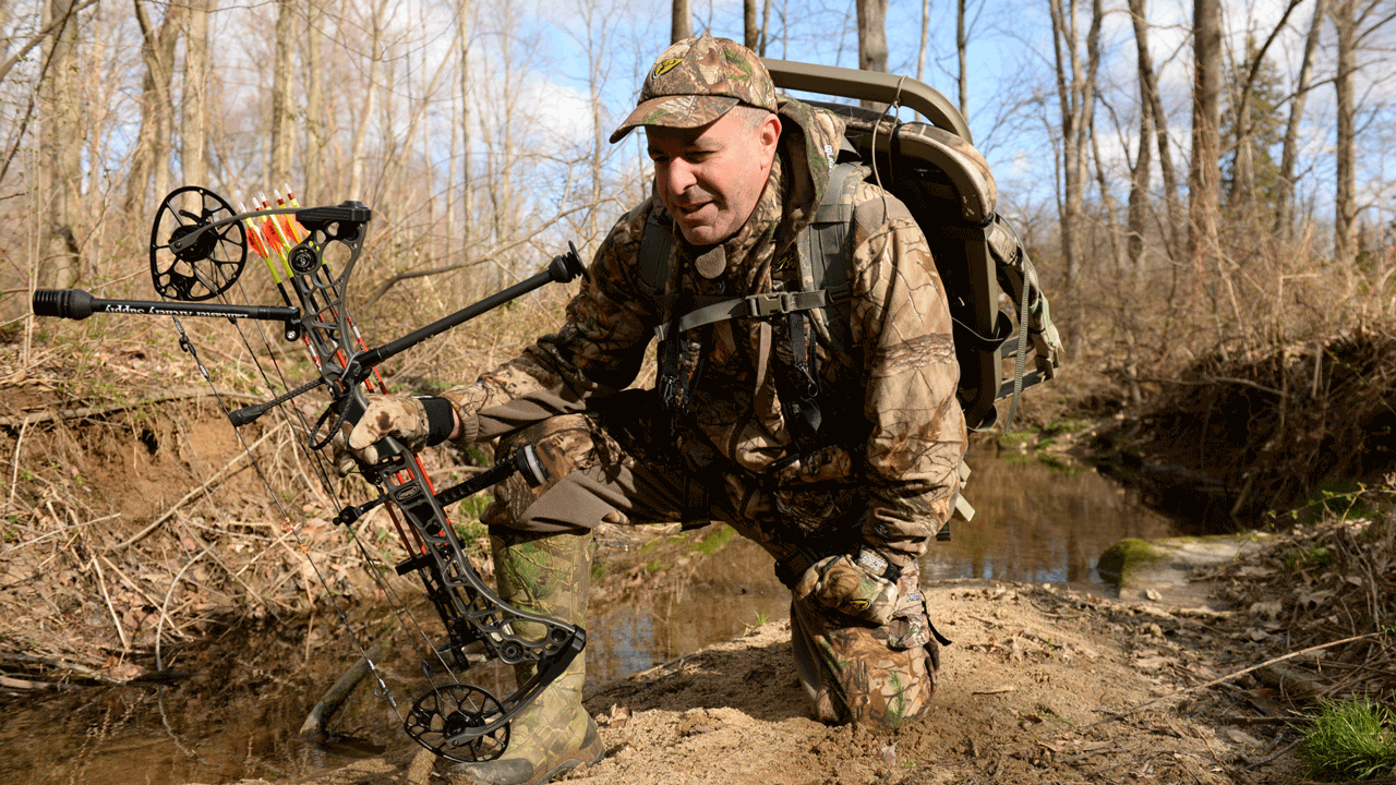 hunter-kneeling-in-creek-with-bow