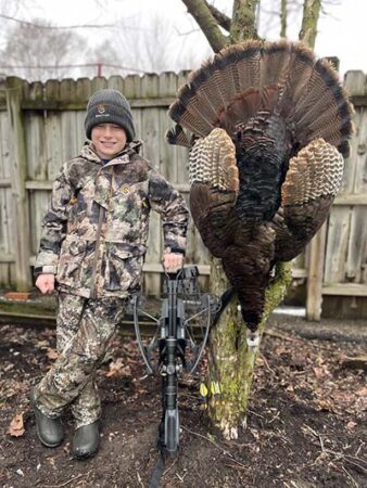 Hunter in camo posing with an Eastern turkey taken with a TenPoint crossbow