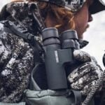 Bowhunter in a saddle, holding Vortex Razor UHD 8x32 binoculars.